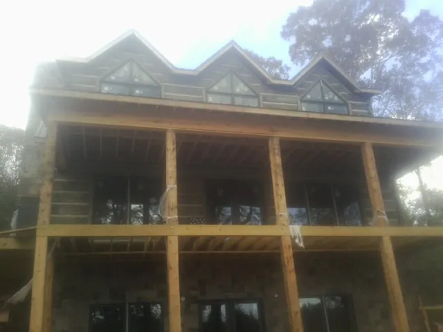 Dormers and porch framing on a large log home under construction — Roof Coating work by our crew in Hartington