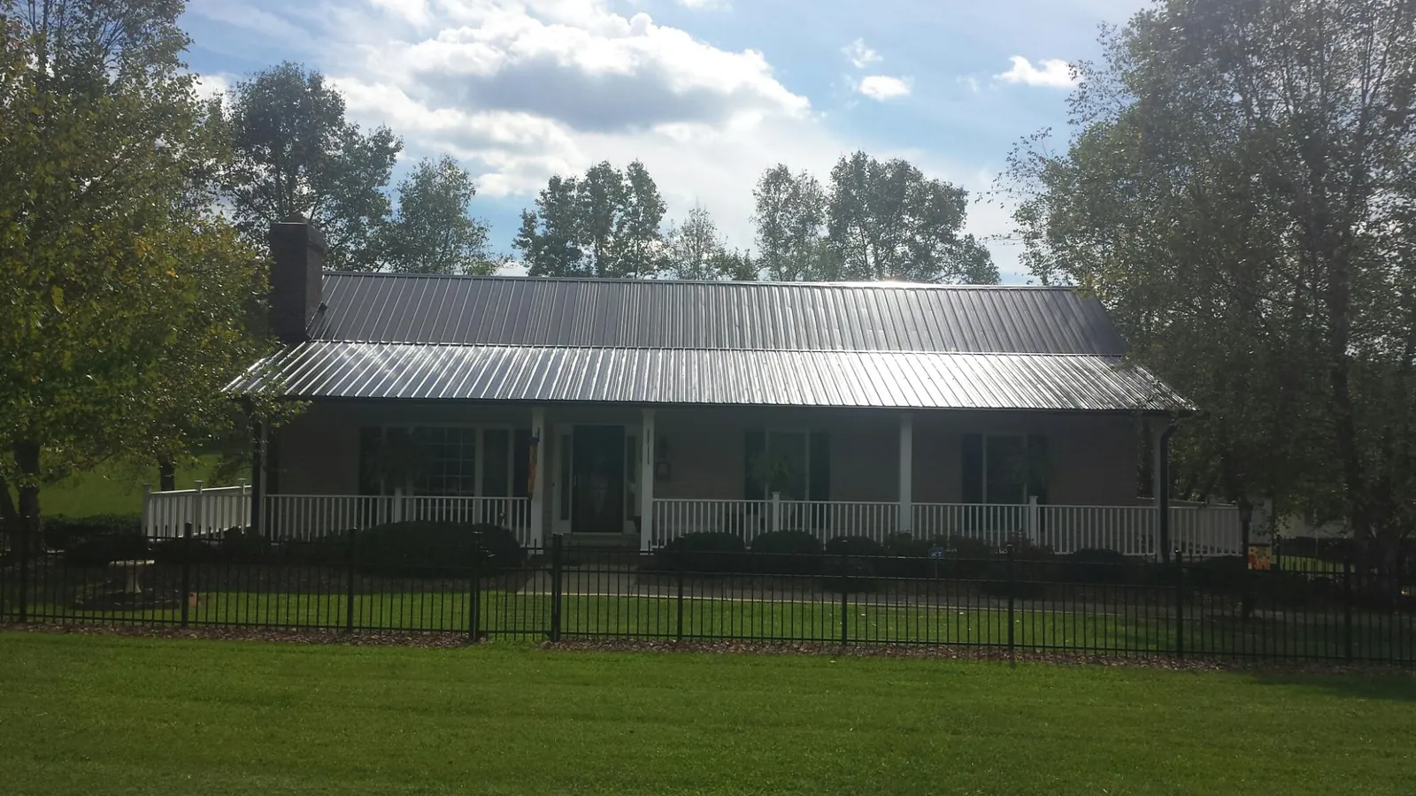 Gray metal roof on a brick ranch with a full width front porch — Gutter Guard Installation work by our crew in Hartington