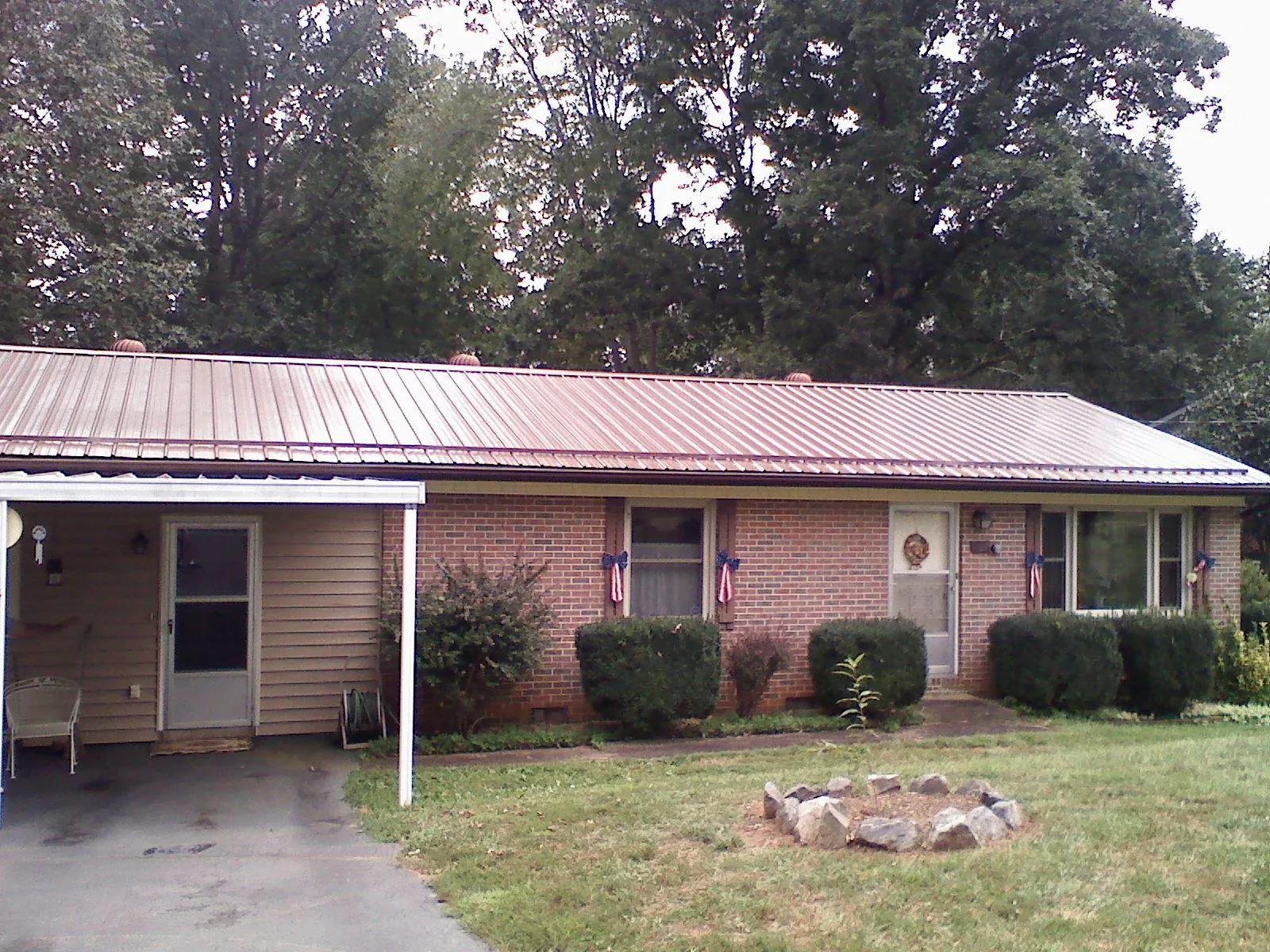 Bronze metal roof and carport on a brick ranch home — Roof Repair work by our crew in Hartington