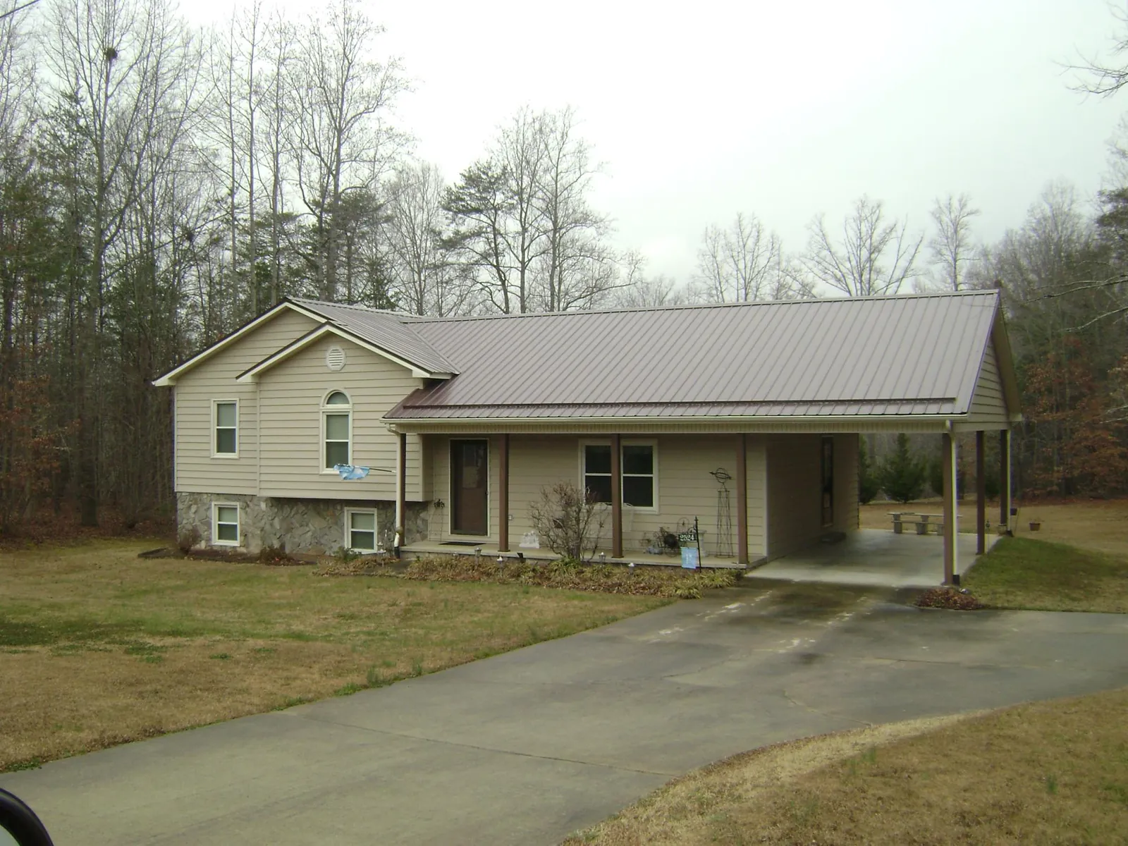 Brown metal roof on a tan split level home with an attached carport in Hartington
