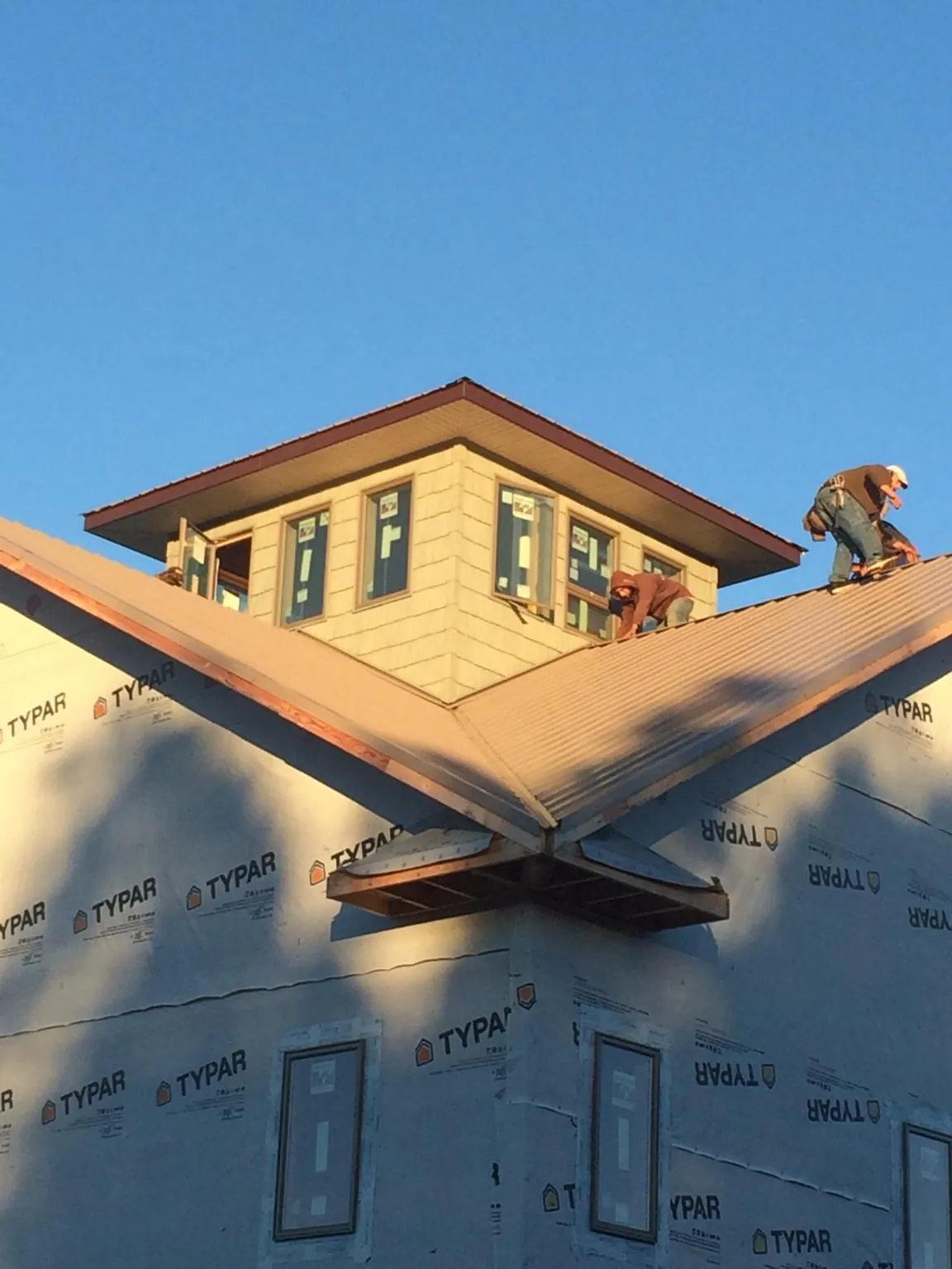 Roofers working around a rooftop cupola on a new metal roof at sunset — Roof Waterproofing in Hartington by Roofing Brothers